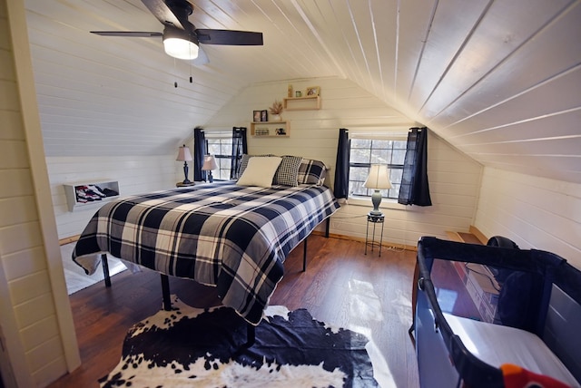 bedroom with wooden walls, vaulted ceiling, ceiling fan, and dark hardwood / wood-style floors