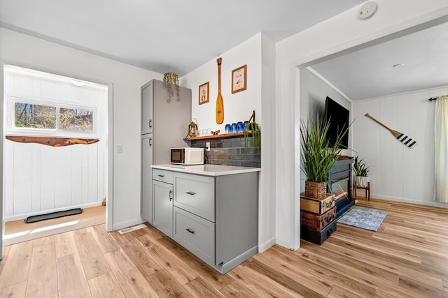 bar featuring baseboards, light wood-type flooring, and white microwave