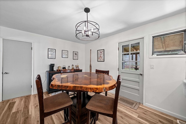 dining area featuring light wood-style floors, baseboards, and an inviting chandelier