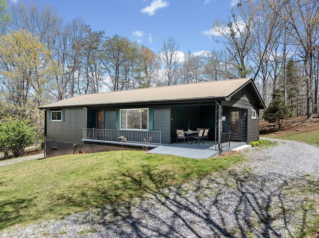 view of front of house featuring a front lawn, a patio, and metal roof