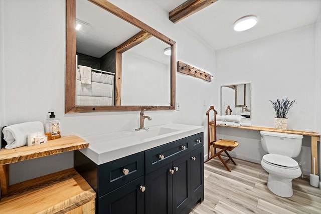 full bath featuring wood finished floors, vanity, a shower with curtain, toilet, and beam ceiling