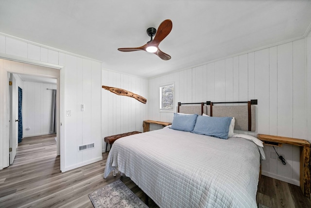 bedroom with wood finished floors, visible vents, ornamental molding, and ceiling fan
