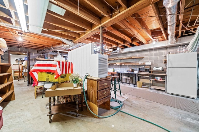 unfinished below grade area with concrete block wall and freestanding refrigerator
