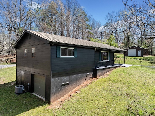 view of side of property featuring an outbuilding, cooling unit, metal roof, a garage, and a yard