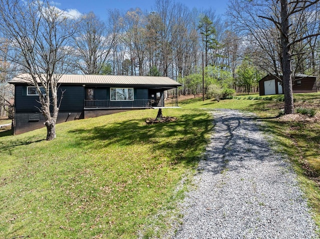 single story home featuring covered porch, an outdoor structure, a front yard, metal roof, and a storage unit