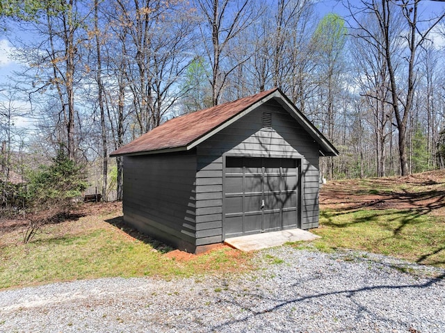 detached garage with a storage unit and gravel driveway