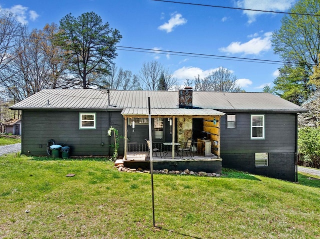 back of house featuring a chimney, a yard, and metal roof