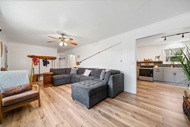 living area featuring ornamental molding, a ceiling fan, and light wood-style flooring