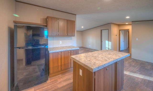 kitchen featuring black refrigerator, hardwood / wood-style floors, a textured ceiling, and a kitchen island