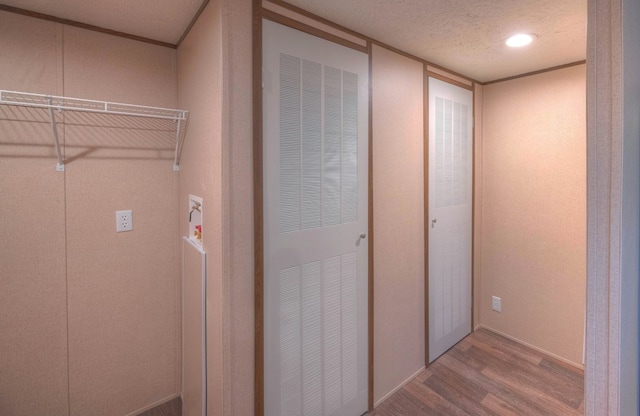 clothes washing area featuring wood-type flooring and a textured ceiling