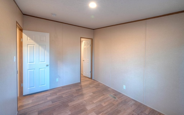 unfurnished bedroom with hardwood / wood-style floors and ornamental molding