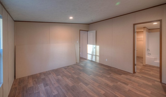 spare room with hardwood / wood-style floors, ornamental molding, and a textured ceiling