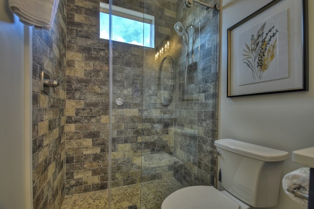 bathroom featuring a shower with door and toilet