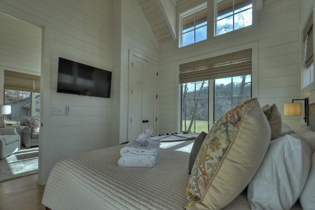 bedroom with high vaulted ceiling, wood-type flooring, access to outside, and multiple windows