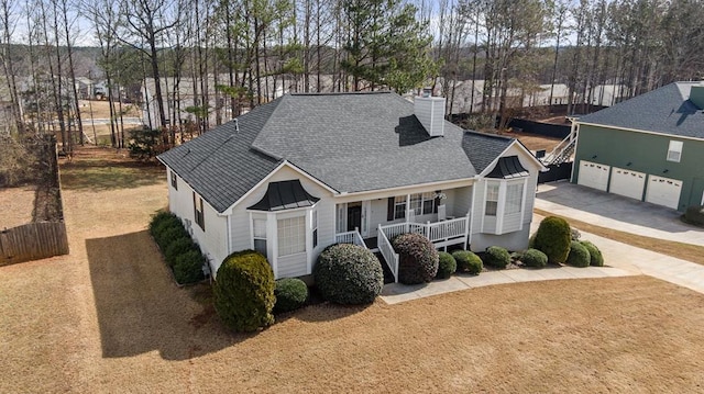 view of front facade featuring a chimney, a shingled roof, covered porch, a garage, and driveway