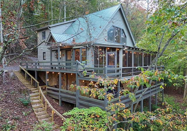 rear view of house featuring a wooden deck and a sunroom