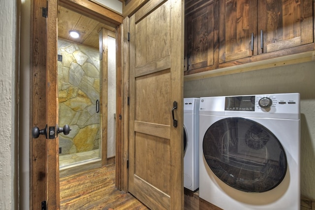 clothes washing area with washer / clothes dryer, dark hardwood / wood-style flooring, and cabinets