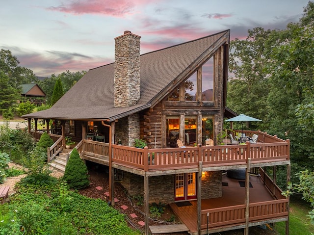 back house at dusk featuring a wooden deck