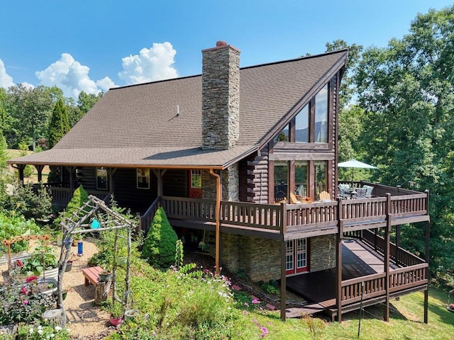 rear view of property featuring a wooden deck, stone siding, log exterior, and a chimney