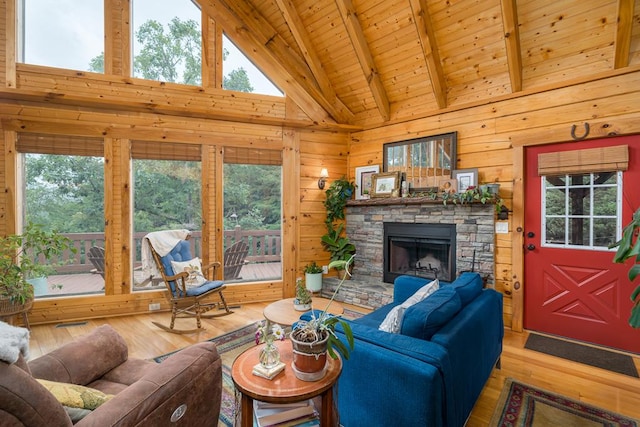 living room with a stone fireplace, wood walls, beamed ceiling, a healthy amount of sunlight, and wooden ceiling