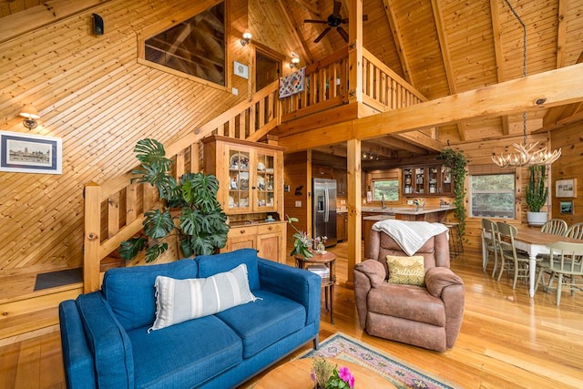 living room featuring beam ceiling, wooden walls, high vaulted ceiling, wooden ceiling, and light wood-type flooring