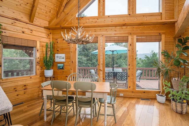 dining room featuring light hardwood / wood-style flooring, plenty of natural light, and wood walls