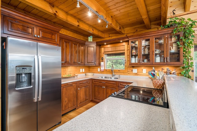 kitchen featuring beamed ceiling, sink, rail lighting, light hardwood / wood-style flooring, and stainless steel fridge