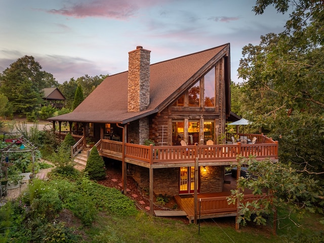 back house at dusk with a wooden deck