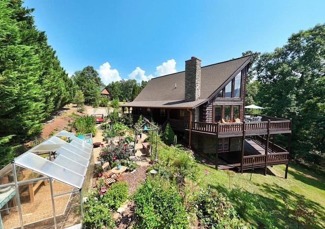 rear view of house featuring a wooden deck and an outbuilding