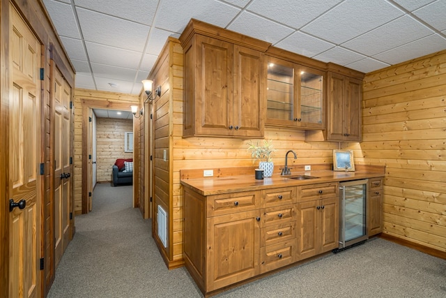 kitchen featuring butcher block counters, beverage cooler, light carpet, and sink