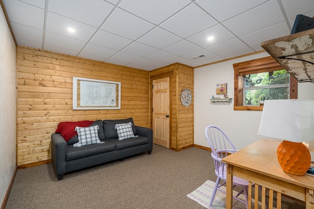 carpeted office featuring a paneled ceiling and wood walls