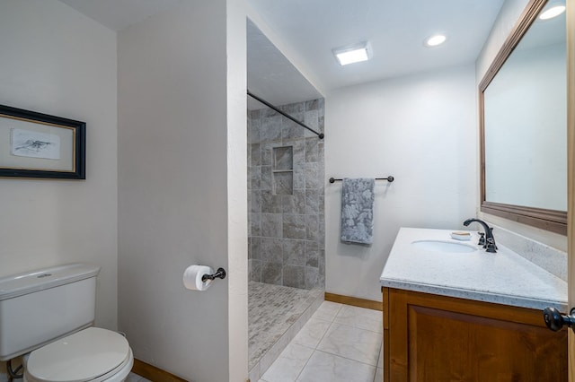 bathroom featuring a tile shower, vanity, and toilet