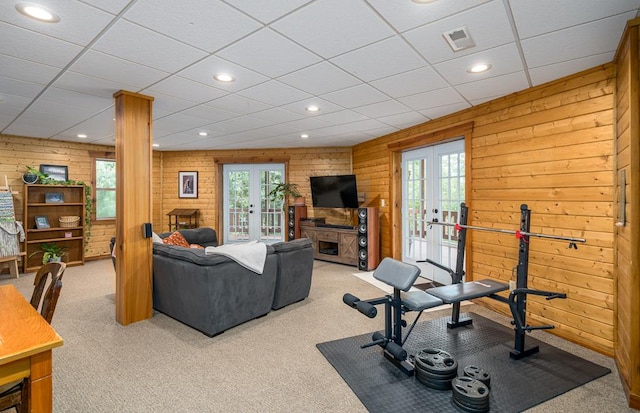 exercise room featuring light carpet, french doors, and wood walls