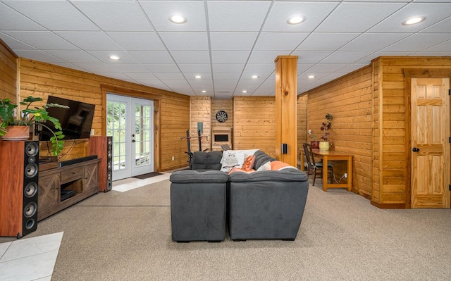 carpeted living room featuring wooden walls and french doors