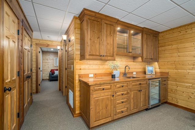 bar with wood counters, sink, light colored carpet, and beverage cooler