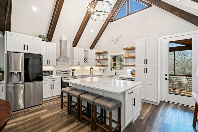 kitchen featuring white cabinetry, wall chimney range hood, a center island, and appliances with stainless steel finishes