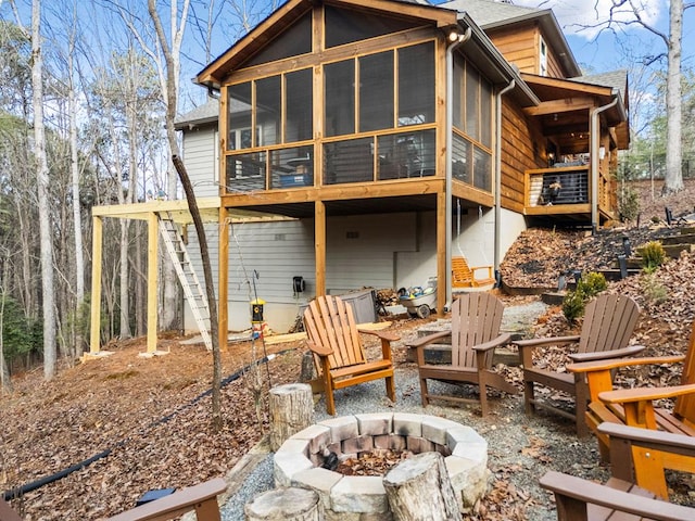 rear view of property with a sunroom and an outdoor fire pit