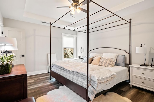 bedroom featuring a tray ceiling and dark hardwood / wood-style flooring