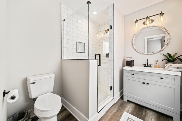 bathroom with wood-type flooring, vanity, an enclosed shower, and toilet