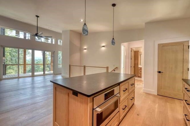 kitchen with pendant lighting, a center island, light wood-type flooring, oven, and light brown cabinets