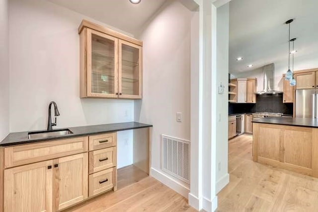 kitchen featuring decorative light fixtures, sink, light brown cabinets, and wall chimney exhaust hood