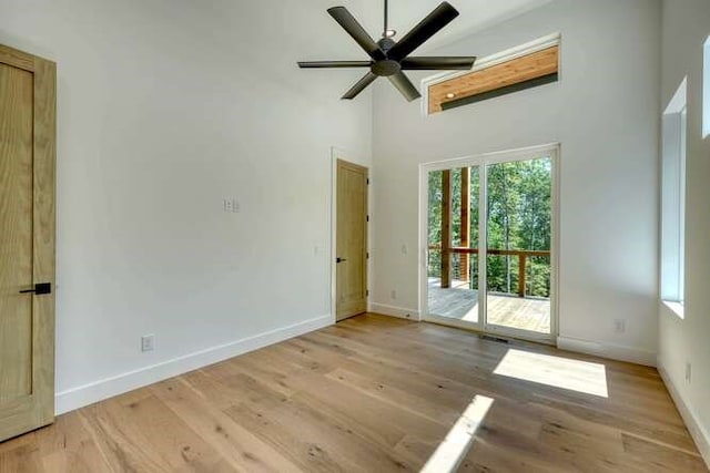 empty room with light hardwood / wood-style flooring, ceiling fan, and a high ceiling