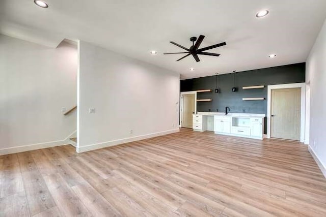 unfurnished living room with ceiling fan, sink, and light hardwood / wood-style flooring