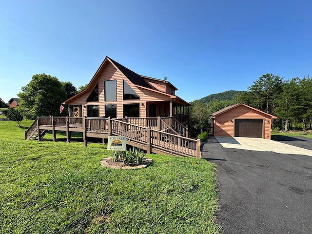 view of front of house featuring aphalt driveway, an outbuilding, a detached garage, and a front yard