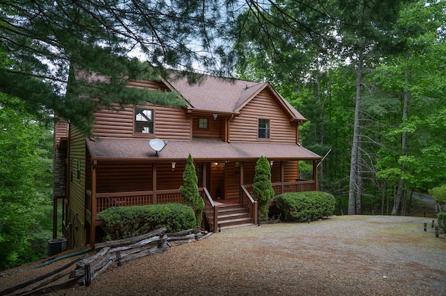 log-style house with covered porch and central air condition unit