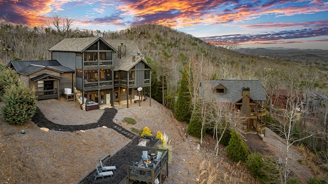 back house at dusk with a sunroom and a mountain view