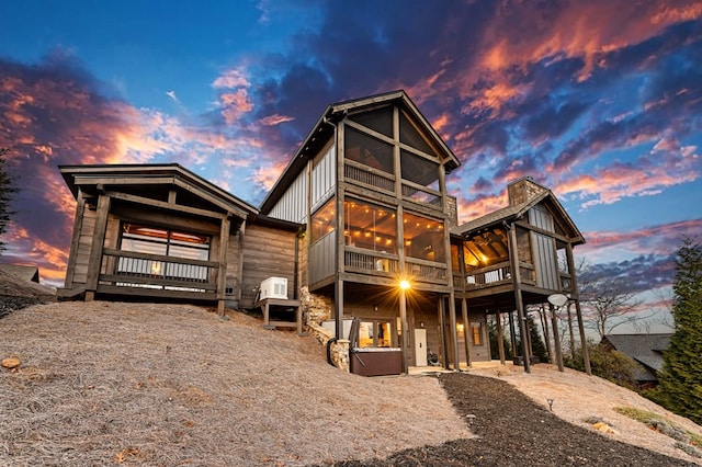 back house at dusk with a sunroom