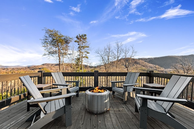 wooden deck with an outdoor fire pit and a mountain view