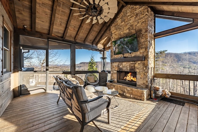 wooden terrace featuring an outdoor stone fireplace and ceiling fan