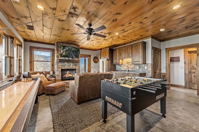 rec room with sink, wooden ceiling, ceiling fan, and a stone fireplace